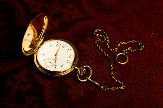 Gold pocket watch on maroon cloth photo