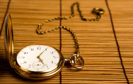 Gold pocket watch on bamboo rugs photo