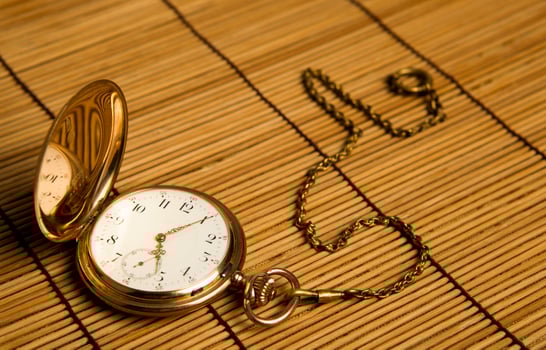 Gold pocket watch on bamboo rugs photo
