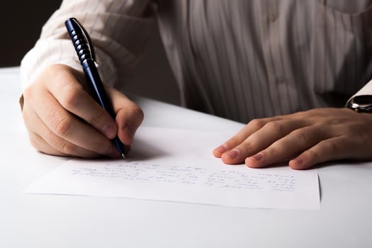 man is writting on a sheet of paper photo