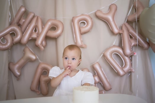 baby girl tries her first birthday cake with mom and pre-teen sister photo