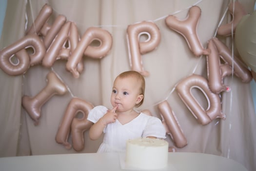 baby girl tries her first birthday cake with mom and pre-teen sister photo