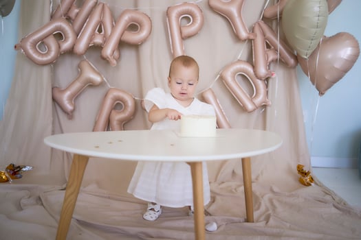 baby girl tries her first birthday cake with mom and pre-teen sister photo