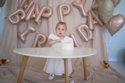 baby girl tries her first birthday cake with mom and pre-teen sister photo