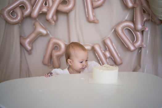 baby girl tries her first birthday cake with mom and pre-teen sister photo