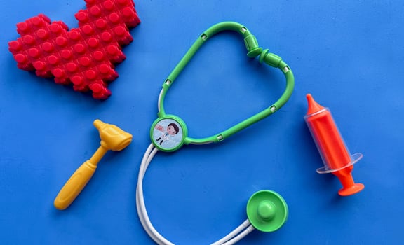 Set of toy medical equipment, syringe, injection, stethoscope, otoscope. Funny blue background and heart shape from toy constructor. Healthy lifestyle concept. photo