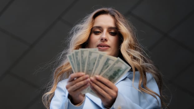 Bottom view successful rich girl business woman buyer holding banknotes dollars in hands counting money salary credit finance thinking holds chin with hand thoughtfully thinks about investment profit photo