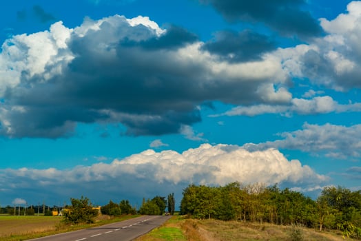 White cumulus thunderclouds in the sky over a highway, Ukraine photo