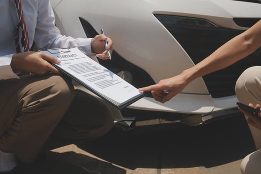 Side view of writing on clipboard while insurance agent examining car after accident photo