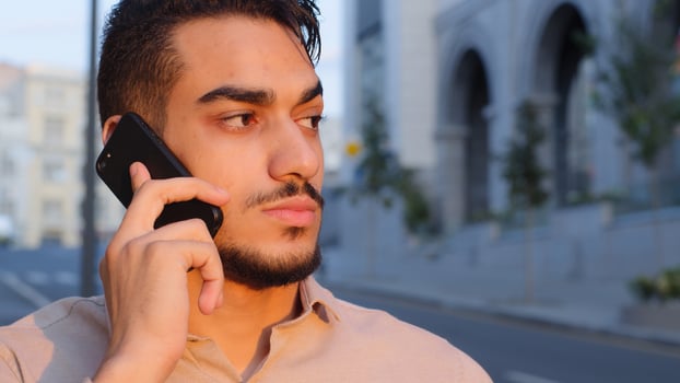 Close-up hispanic emotional business man bearded serious guy talking on mobile phone answering call using smartphone remote talk cellular connection standing in city outside cellphone negotiation photo