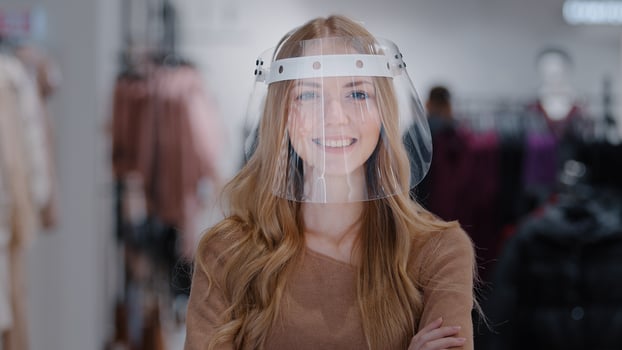 Close-up confident protected store manager girl shop assistant in transparent plastic mask shield portrait woman smiling female buyer looking at camera concept virus spread protection pandemic control photo