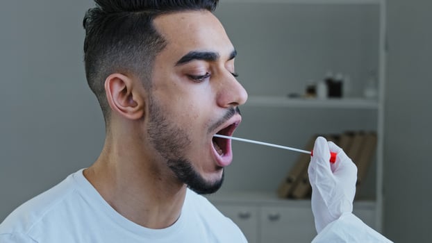 Close-up spanish man arabic male patient opens mouth donates saliva sample for infection virus, unrecognizable nurse medical worker doing pcr test with equipment for covid-19 coronavirus to ethnic guy photo
