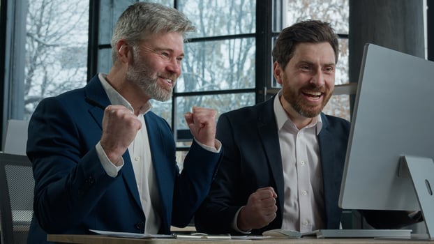 Two businessmen men business partner colleagues collaboration in office working on computer brainstorm in corporate teamwork get good news win deal celebrating victory in online game rejoice success photo
