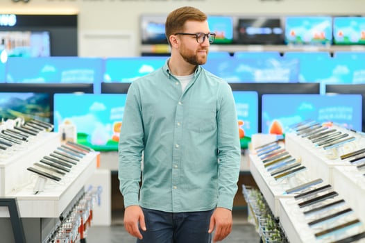 A man stands near mobile phones in an electronics store. photo