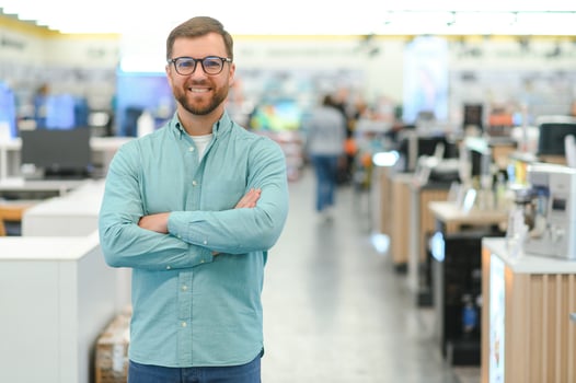 A man stands near mobile phones in an electronics store. photo