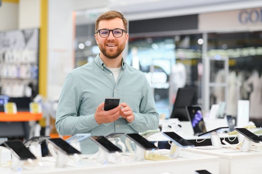 happy young man choosing a new mobile in a tech store photo