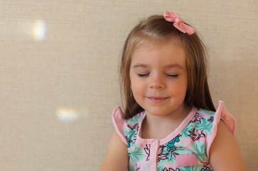 Cute adorable smiling little girl with closed eyes against beige wall indoors photo