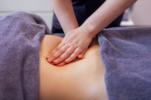 Close up of young female hands doing belly massage in a beauty salon or clinic. photo