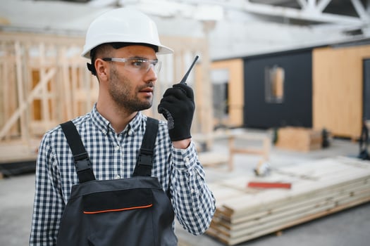 An engineer controls the production of modular houses and uses a walkie-talkie photo
