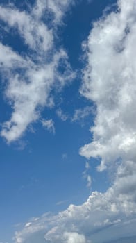 A serene image of a clear blue sky with fluffy white clouds gently floating across the horizon, creating a peaceful and calm atmosphere. copy space. photo