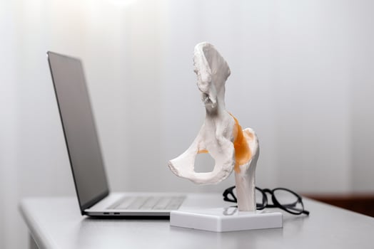 Close-up of a spine model on a physiotherapist's desk, alongside a laptop and glasses. Ideal for depicting spinal treatment procedures and orthopedic care in a modern medical environment photo