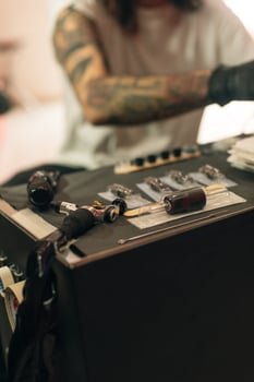 Tattoo artist workplace with machine and bottles with black tattoo in photo