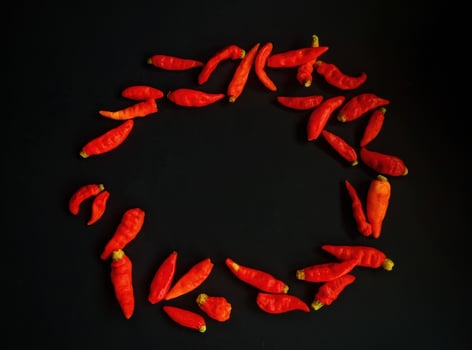 A circle of red peppers arranged in a circle on a black background photo