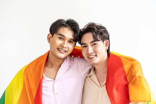 Guys spend time together at home, Portrait of Happy Asian gay couple embracing and showing their love under lgbt colorful rainbow flag. LGBT and love concept. photo