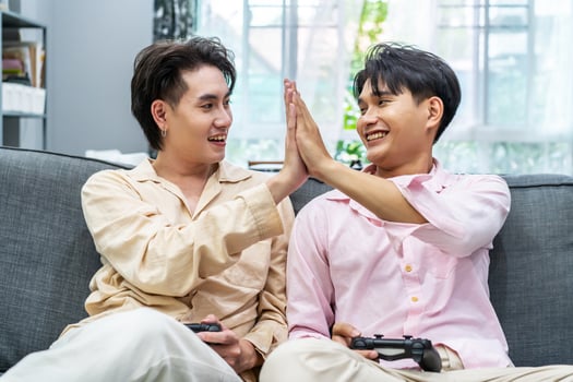 Two young males relax on weekend sit on couch enjoy console game push buttons on controllers, Two Male Players spend free time together play online game photo