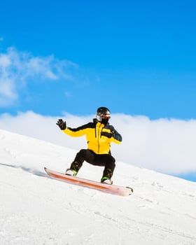 Side view male snowboarder wear yellow black on piste ski downhill fast motion in Alps. Active winter holidays, skiing downhill in overcast day. Ski rides on the track with swirls of fresh snow photo