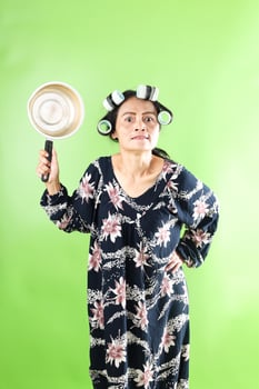 Angry Asian House Maid Wearing Daster Standing While Holding Noodle Pan photo