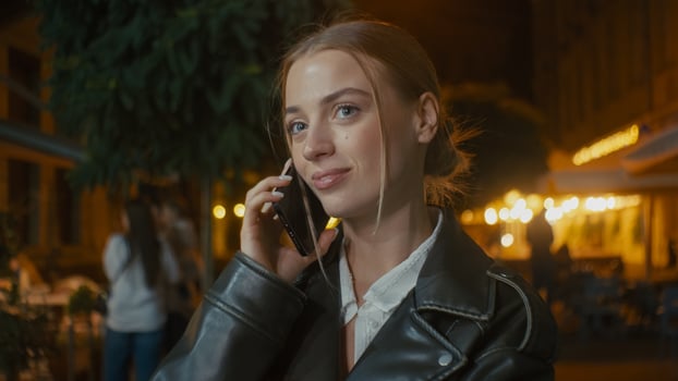 European young woman talking chatting gossiping mobile phone smartphone cellphone friendship evening city outside discuss girl smiling laughing model urban girlfriend street weekend enjoyment dialogue photo