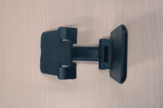 Black cell phone stand shot from the side of high engel. portable cell phone holder on wood textured background photo