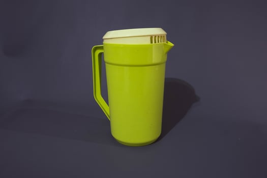 Green plastic waterpot, isolated on grey background. photo