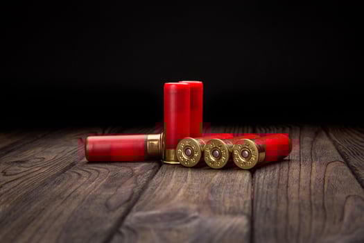 Shotgun cartridges on a brown wooden table. Ammunition for 12 gauge smoothbore weapons. Hunting ammunition. photo