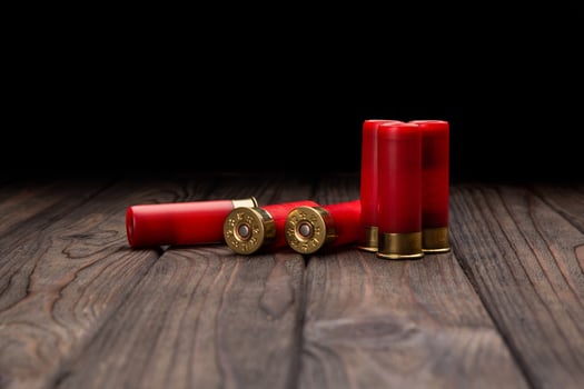 Shotgun cartridges on a brown wooden table. Ammunition for 12 gauge smoothbore weapons. photo