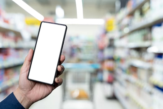 Personal perspective of a woman's hand holding up a smartphone while grocery shopping in supermarket photo