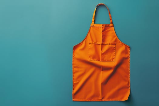 Bright orange apron hanging against a teal backdrop in a kitchen setting, ready for culinary adventures photo