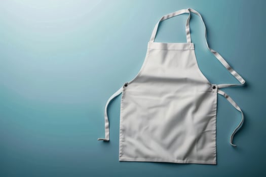 A crisp white apron draped against a smooth turquoise backdrop, inviting culinary adventures in a sunlit kitchen photo