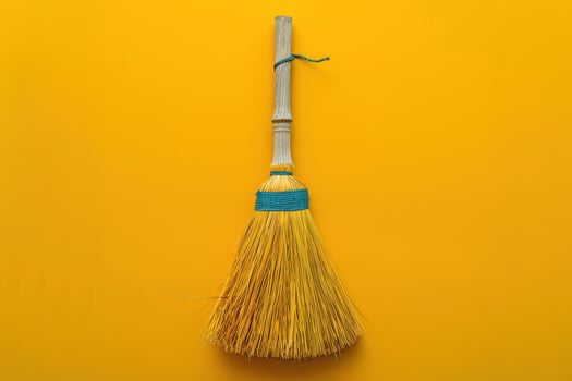 A bright yellow broom with a blue band stands against a vivid yellow backdrop, embodying the essence of cleanliness and simplicity photo