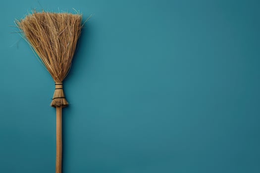 A rustic broom resting against a teal wall, evoking a sense of simplicity and charm in a cozy space photo