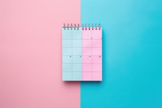 A spiral-bound calendar rests on a pastel pink and blue background, suggesting a fresh start or new beginnings in planning photo