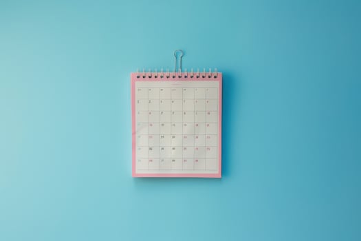 A colorful desk calendar hanging against a bright blue wall, marking important dates and events for the month ahead photo