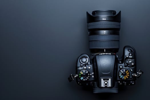 A sleek camera lays on a dark surface with a zoom lens, ready to capture stunning moments of life at any time photo