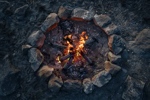 Nighttime campfire surrounded by rocks, glowing embers illuminating the darkness in a serene outdoor setting photo