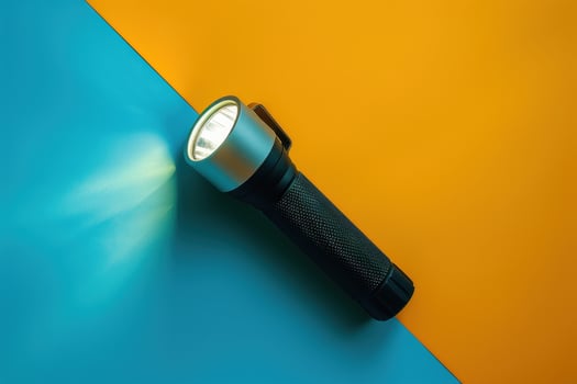 A sleek flashlight illuminating a vibrant split background of blue and orange colors photo