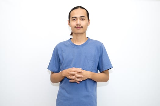 Smiling Asian man wearing dark blue t-shirt standing with crossed fingers and facing forward. isolated in white background photo