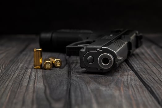black pistol and cartridges on a wooden background photo