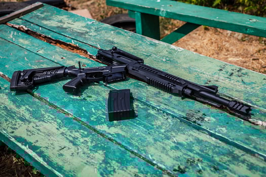 Black automatic shotgun on a green wooden table photo