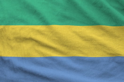 Gabon flag depicted on folded wavy fabric of old cloth photo